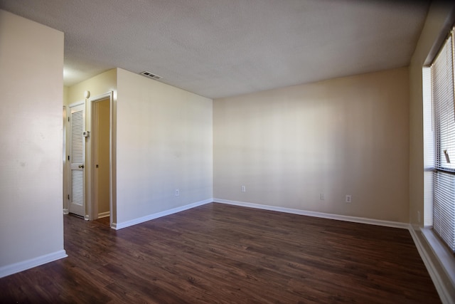 spare room with a textured ceiling and dark hardwood / wood-style flooring