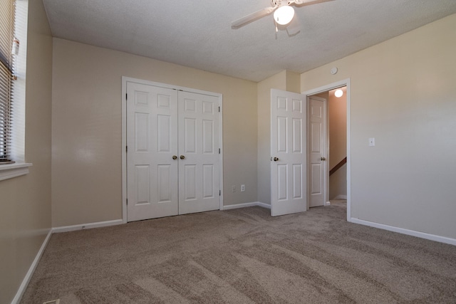 unfurnished bedroom with a closet, ceiling fan, light colored carpet, and a textured ceiling