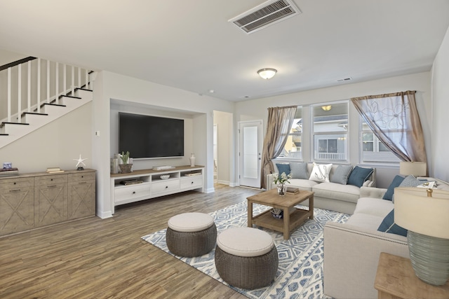 living area featuring stairs, wood finished floors, visible vents, and baseboards