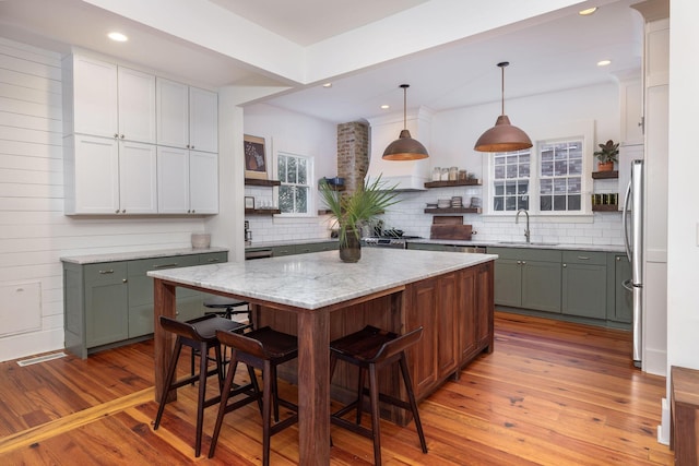 kitchen with decorative light fixtures, a kitchen island, a breakfast bar, sink, and light hardwood / wood-style flooring