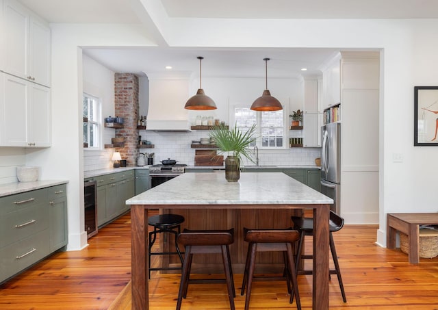 kitchen featuring wine cooler, premium range hood, pendant lighting, white cabinetry, and appliances with stainless steel finishes