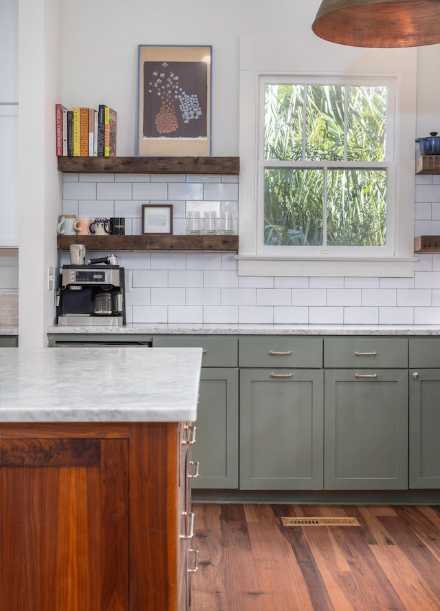 kitchen with dark wood-type flooring, decorative backsplash, and light stone counters