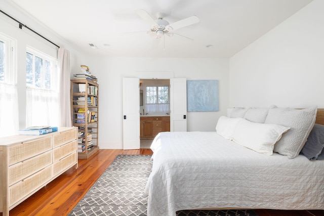 bedroom with ceiling fan, wood-type flooring, and ensuite bathroom