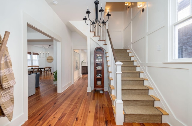 staircase with hardwood / wood-style floors and an inviting chandelier