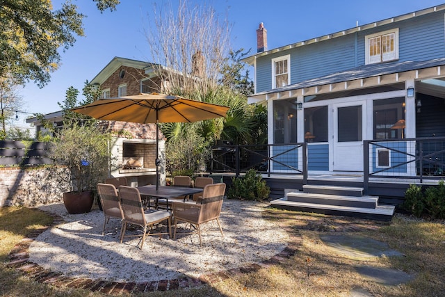 rear view of property featuring a fireplace, a deck, and a sunroom