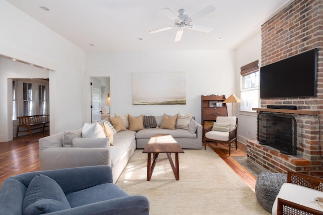 living room with ceiling fan, hardwood / wood-style floors, and a brick fireplace