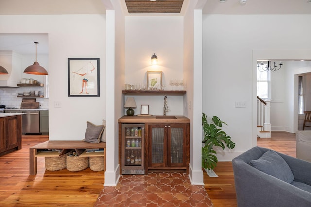 interior space with a chandelier, wine cooler, wood-type flooring, and sink