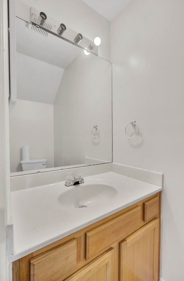 bathroom featuring vanity, toilet, and lofted ceiling