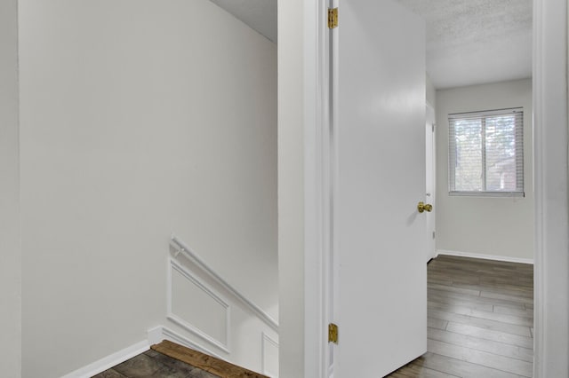 hall with a textured ceiling and dark hardwood / wood-style floors