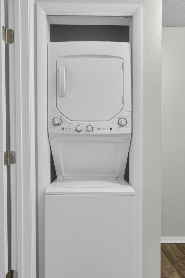 washroom featuring dark hardwood / wood-style flooring and stacked washer and dryer