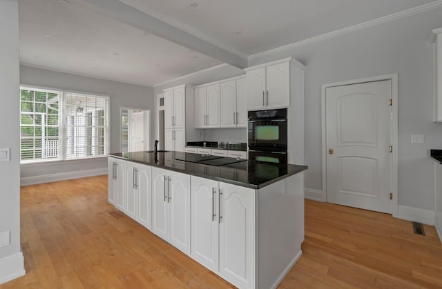 kitchen featuring light hardwood / wood-style floors, a kitchen island, black appliances, white cabinets, and sink