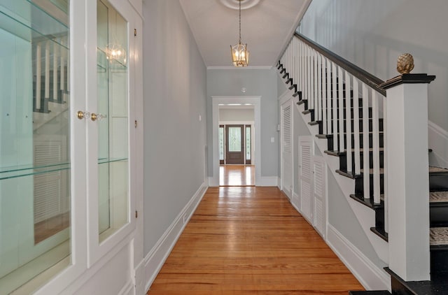 corridor with a chandelier, french doors, ornamental molding, and hardwood / wood-style floors