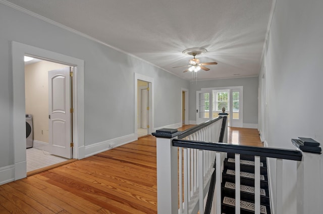 stairs featuring washer / dryer, ceiling fan, ornamental molding, and light hardwood / wood-style flooring