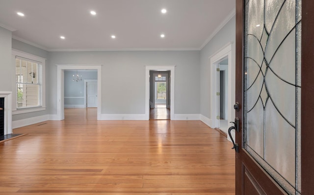 foyer with a healthy amount of sunlight, ornamental molding, and light wood-type flooring