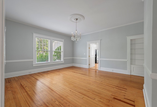 empty room with an inviting chandelier, built in features, ornamental molding, and light wood-type flooring