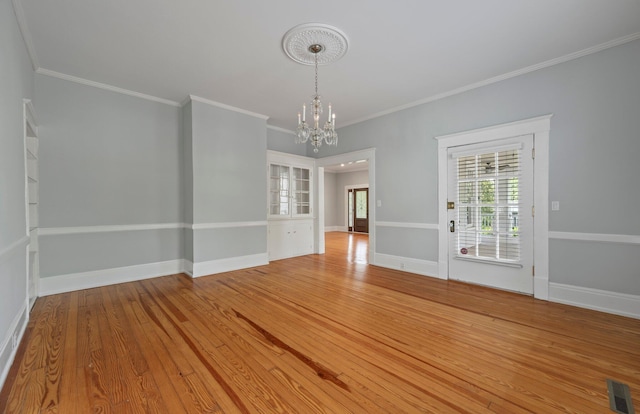 unfurnished room featuring crown molding, a chandelier, and wood-type flooring