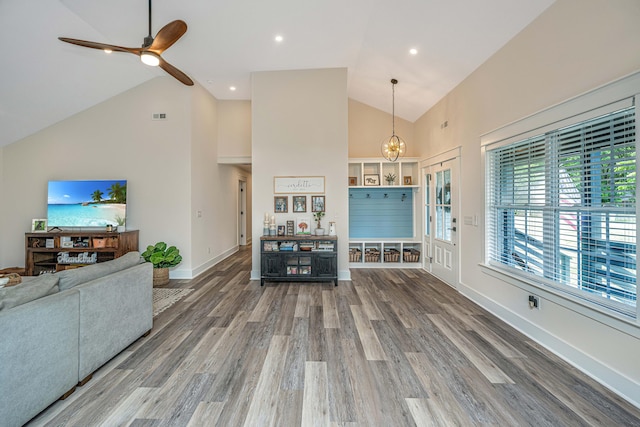 living room with high vaulted ceiling, hardwood / wood-style flooring, and ceiling fan with notable chandelier