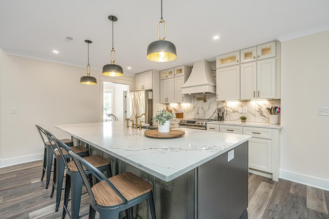 kitchen with stainless steel appliances, dark wood-type flooring, an island with sink, and premium range hood