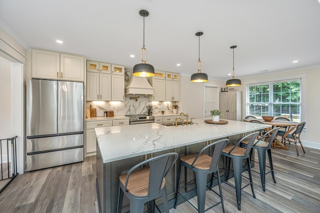 kitchen with a spacious island, custom range hood, stainless steel appliances, wood-type flooring, and tasteful backsplash