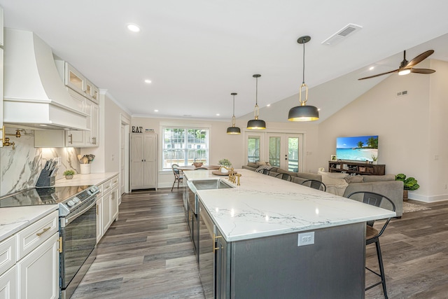 kitchen with a center island with sink, ceiling fan, hardwood / wood-style flooring, electric range, and premium range hood