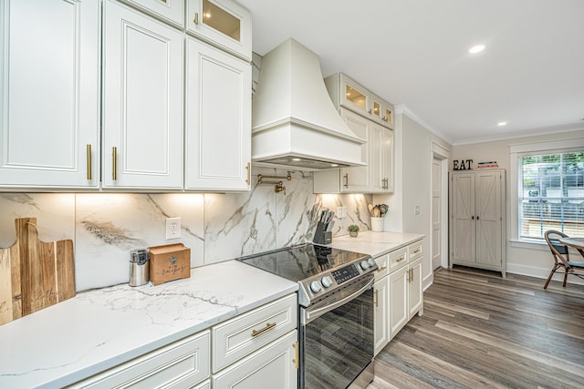 kitchen featuring dark wood-type flooring, ornamental molding, custom range hood, stainless steel electric stove, and tasteful backsplash