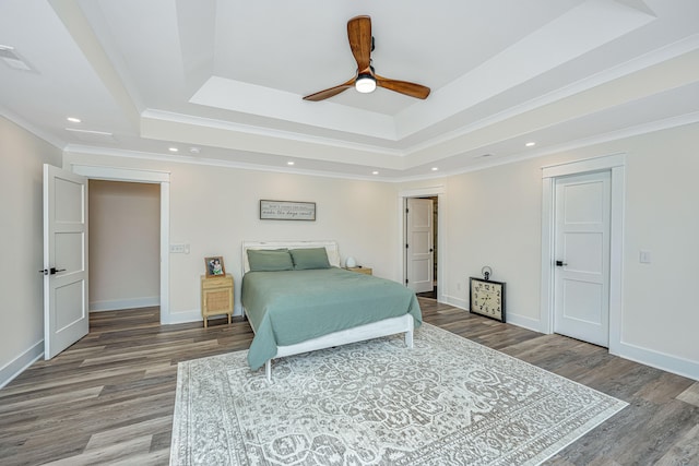 bedroom with ceiling fan, a raised ceiling, crown molding, and hardwood / wood-style flooring