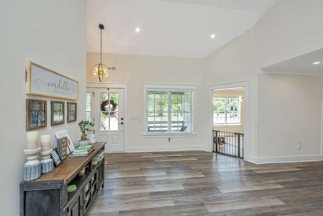 foyer featuring high vaulted ceiling, a chandelier, a wealth of natural light, and dark wood-type flooring