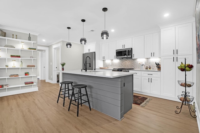 kitchen with sink, stainless steel appliances, light hardwood / wood-style floors, a kitchen island with sink, and white cabinets