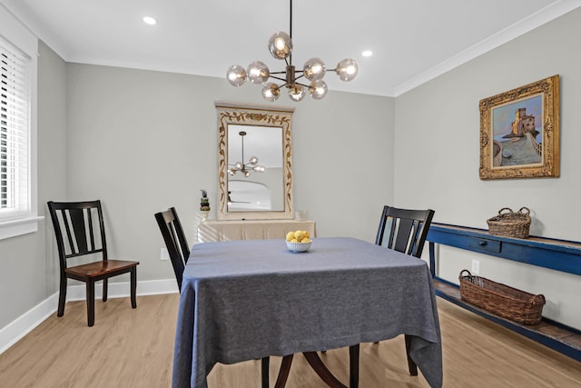 dining area with light wood-type flooring, ornamental molding, and an inviting chandelier