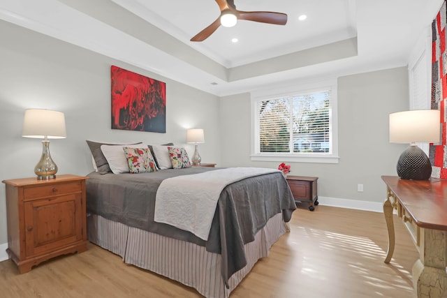 bedroom with light hardwood / wood-style floors, a raised ceiling, ceiling fan, and crown molding