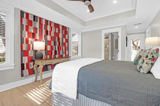 bedroom featuring a raised ceiling, ceiling fan, ornamental molding, connected bathroom, and wood-type flooring