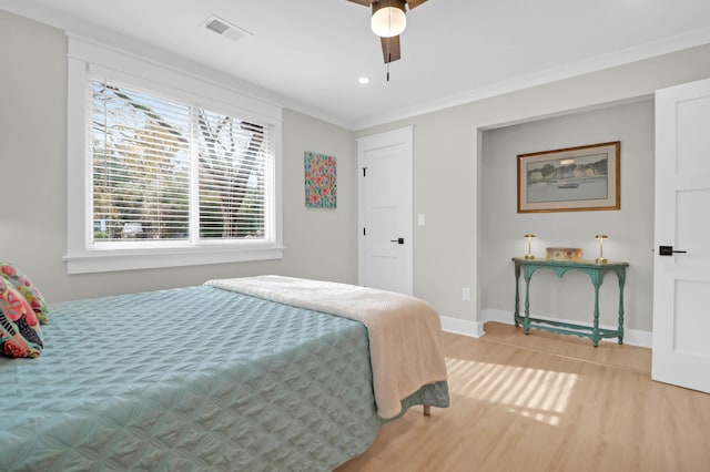 bedroom with light hardwood / wood-style floors, ceiling fan, and crown molding