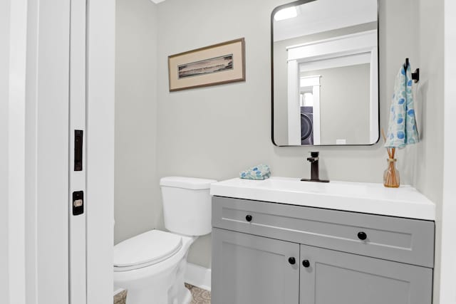 bathroom featuring washer / dryer, vanity, and toilet