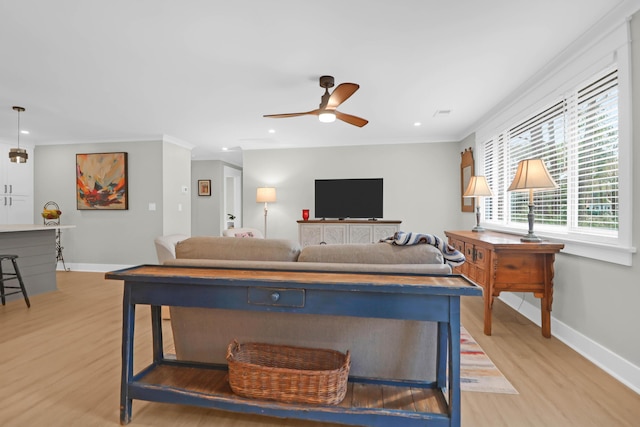 living room featuring ceiling fan, light wood-type flooring, and ornamental molding