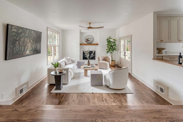 living room with a fireplace, ceiling fan, and dark hardwood / wood-style flooring