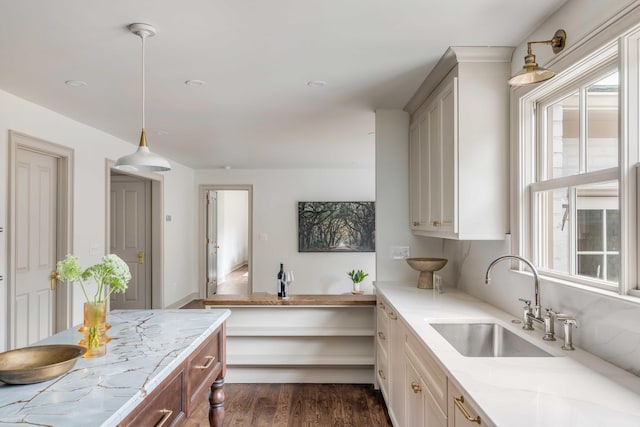 kitchen with dark hardwood / wood-style floors, light stone countertops, sink, and hanging light fixtures