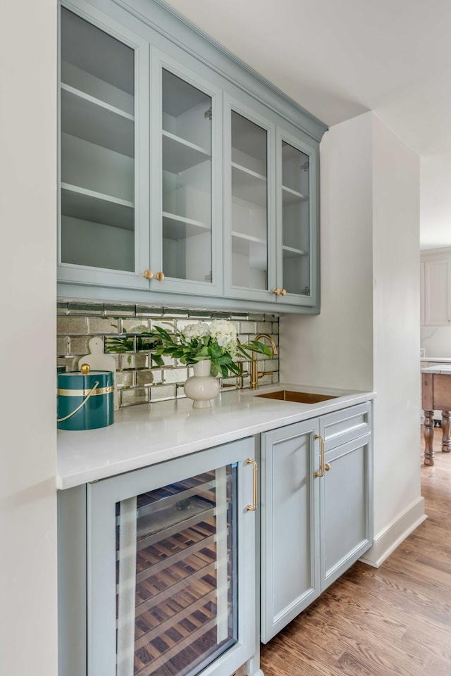 bar with sink, wine cooler, and light hardwood / wood-style flooring