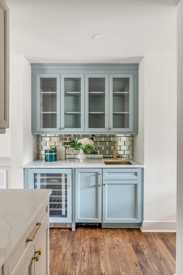 bar with light stone countertops, sink, wine cooler, dark hardwood / wood-style floors, and decorative backsplash