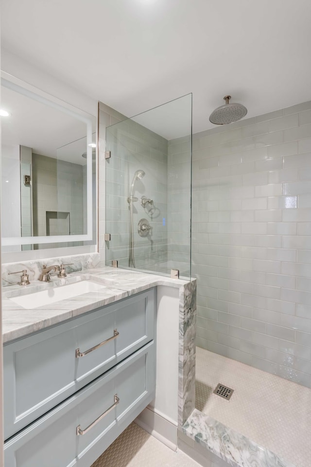 bathroom with tiled shower and vanity