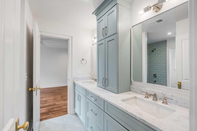 bathroom with tile patterned flooring, vanity, and tiled shower