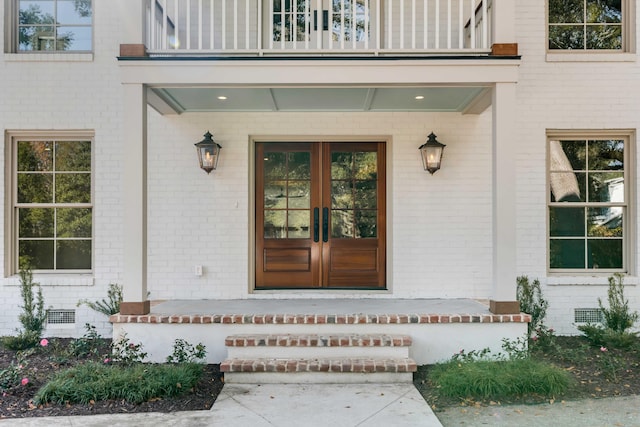 doorway to property with french doors, a balcony, and a porch