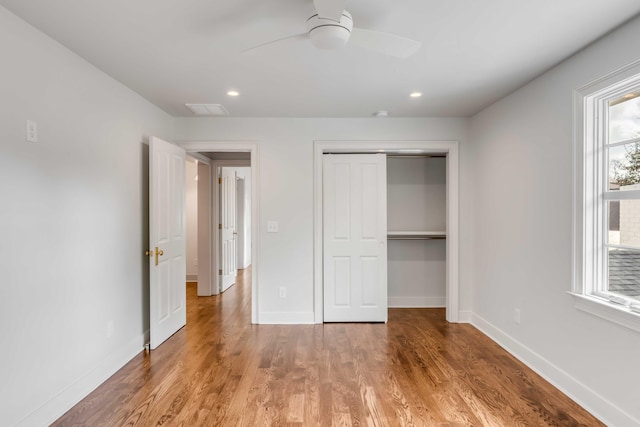 unfurnished bedroom with multiple windows, a closet, ceiling fan, and hardwood / wood-style flooring