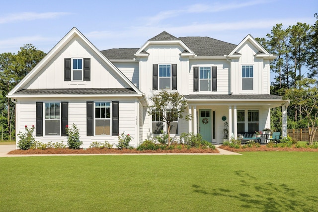 view of front of home featuring board and batten siding, a front lawn, covered porch, and roof with shingles