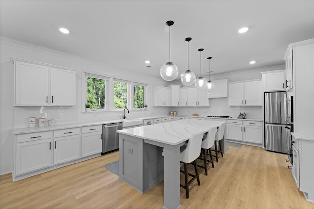 kitchen featuring appliances with stainless steel finishes, a kitchen island, white cabinetry, decorative backsplash, and ornamental molding