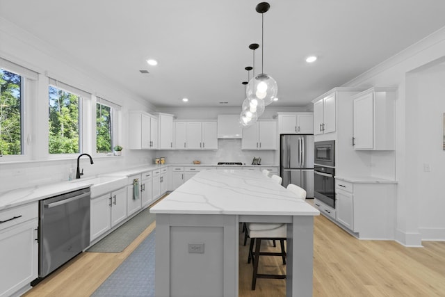 kitchen featuring appliances with stainless steel finishes, a kitchen island, decorative backsplash, white cabinets, and ornamental molding