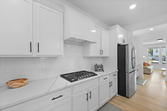 kitchen featuring stainless steel appliances, premium range hood, white cabinetry, recessed lighting, and light stone counters