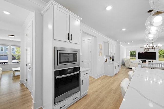 kitchen with stainless steel appliances, open floor plan, light wood finished floors, white cabinets, and recessed lighting