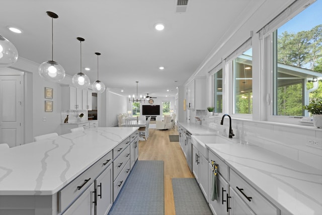 kitchen featuring healthy amount of natural light, light wood finished floors, decorative backsplash, and recessed lighting