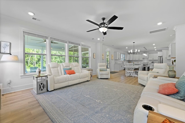 living room with ceiling fan, light wood-style flooring, recessed lighting, baseboards, and a chandelier