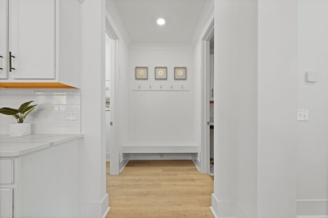 corridor featuring light wood-style floors, crown molding, and recessed lighting